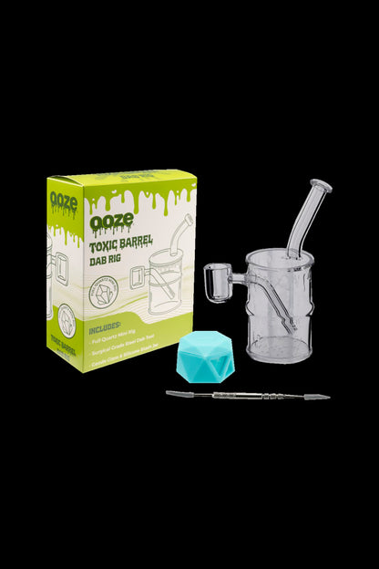 Ooze Toxic Barrel dab rig kit with glass water pipe, quartz banger, dab tool, and blue ice cube cooling insert, displayed with its packaging.