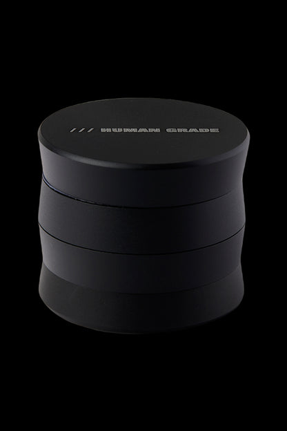Black four-piece cannabis grinder with "HUMAN GRADE" etched on the lid.