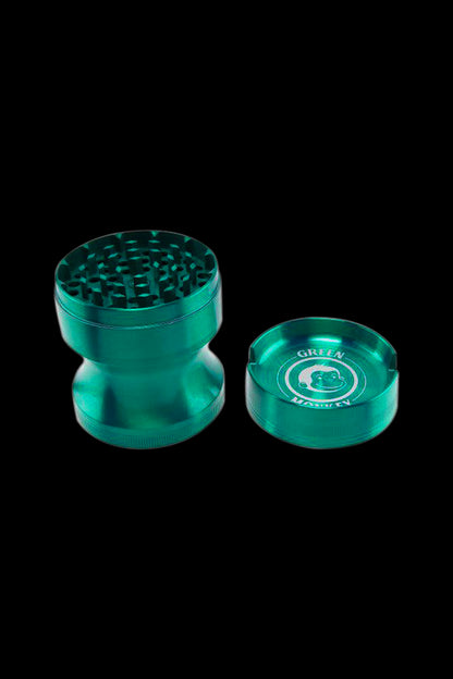 Close-up, angled view of the metallic Green Monkey Chacma Grinder with Ashtray in blue-green with its ridged grinder top and separate ashtray lid showing the logo.