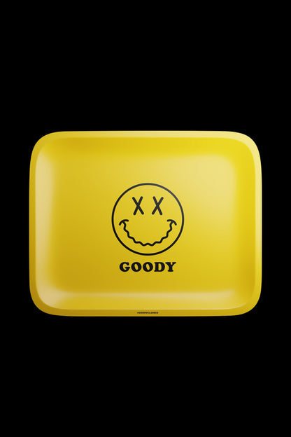 The Goody Glass Yellow Big Face Rolling Tray is pictured from above, showing a square yellow tray with a smiling face graphic.