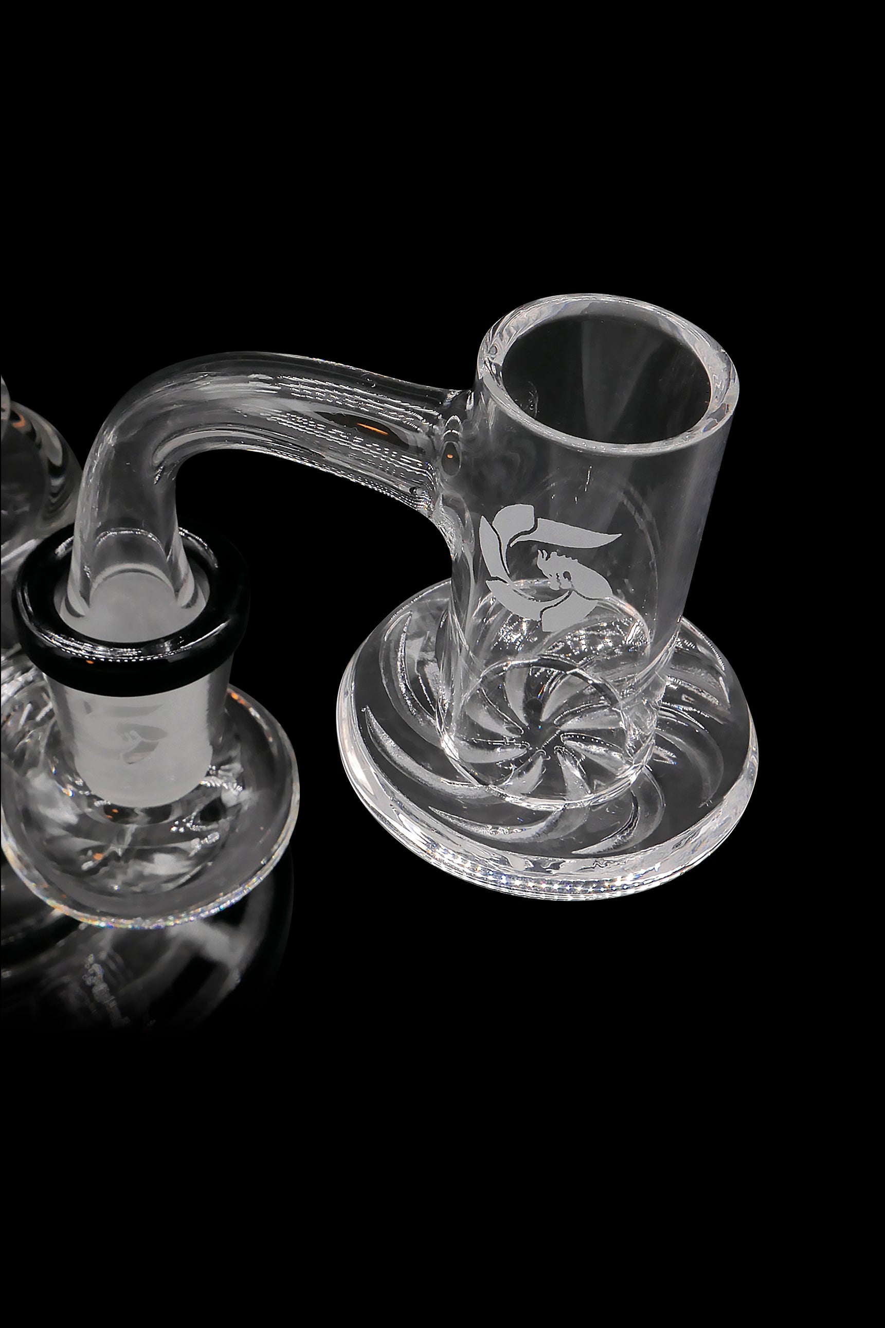 Clear glass cannabis dab rig with intricate swirling patterns and handle, isolated on a black background.