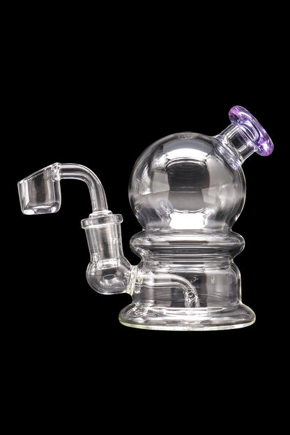 Clear glass dab rig with spherical chamber and quartz banger.