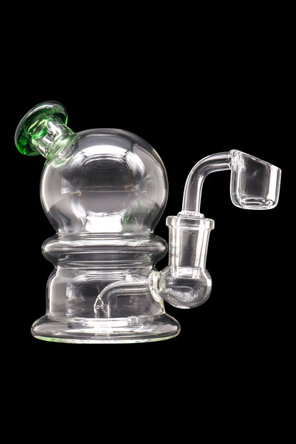 Clear glass dab rig with green accents and a quartz banger.