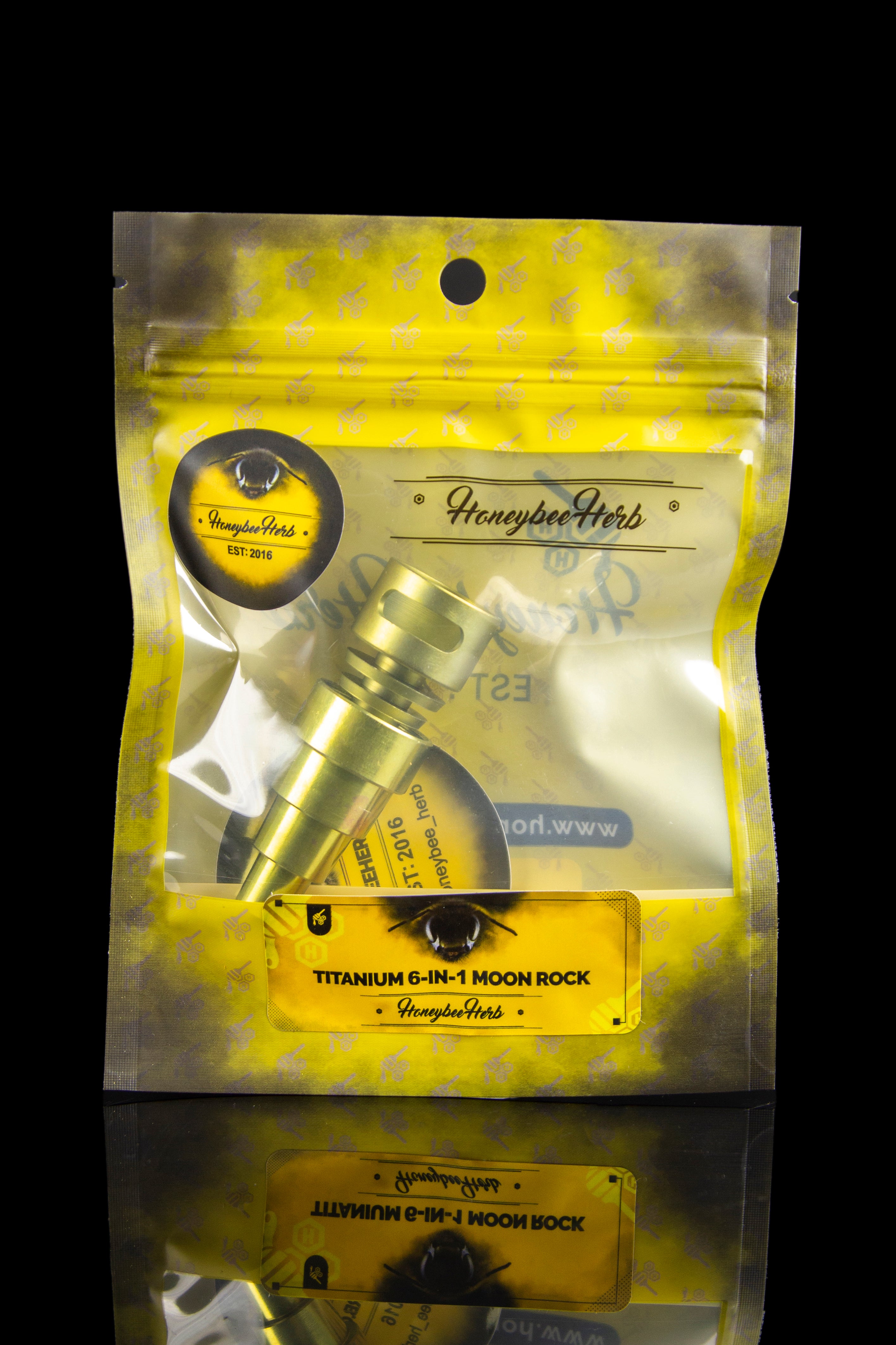 Gold mylar bag containing cannabis accessories, labeled “Honeybee Herb Titanium 6-in-1 Moon Rock.”