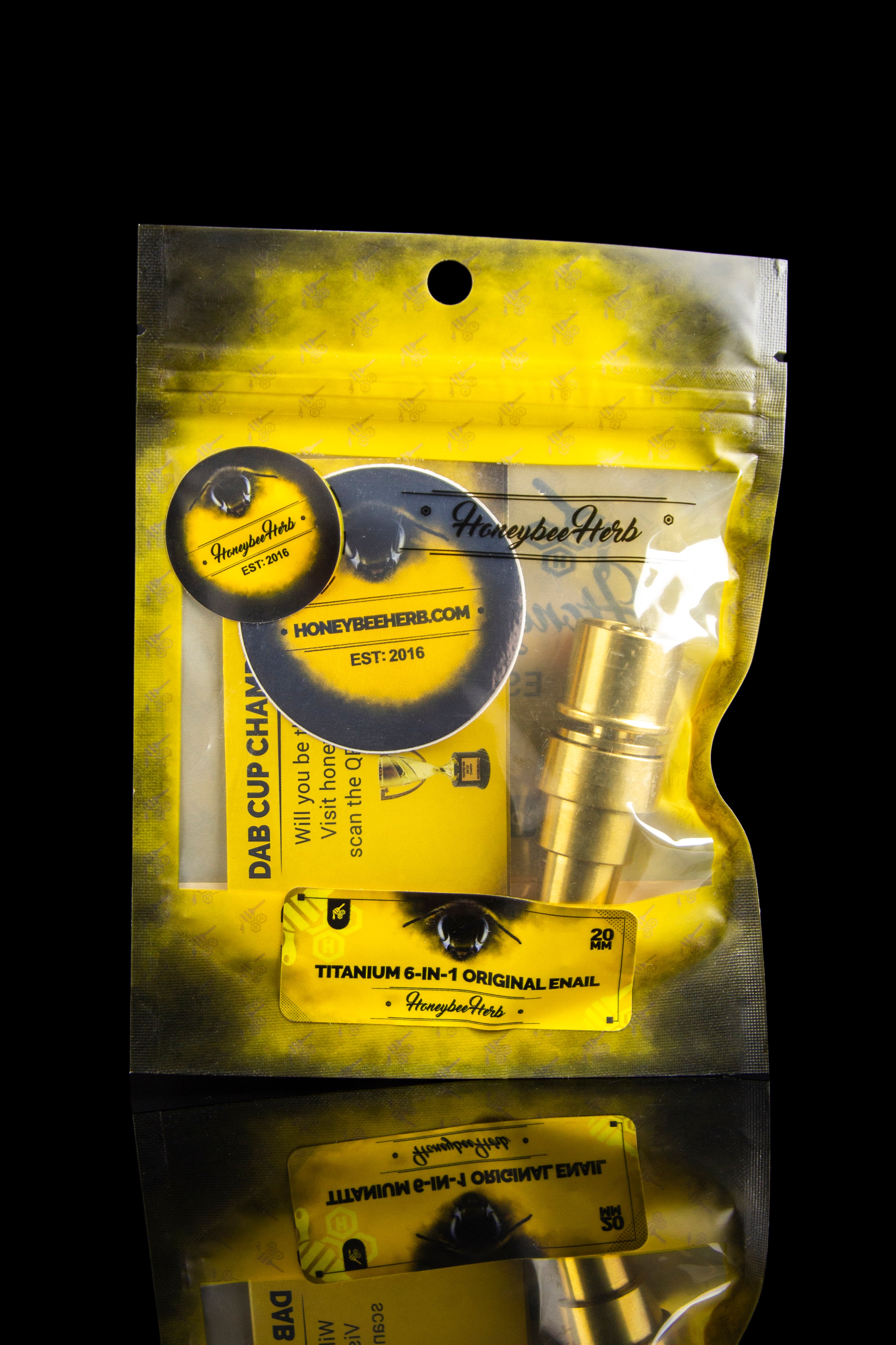 Gold metallic mylar bag labeled "Honeybee Herb" containing cannabis dabbing accessories.