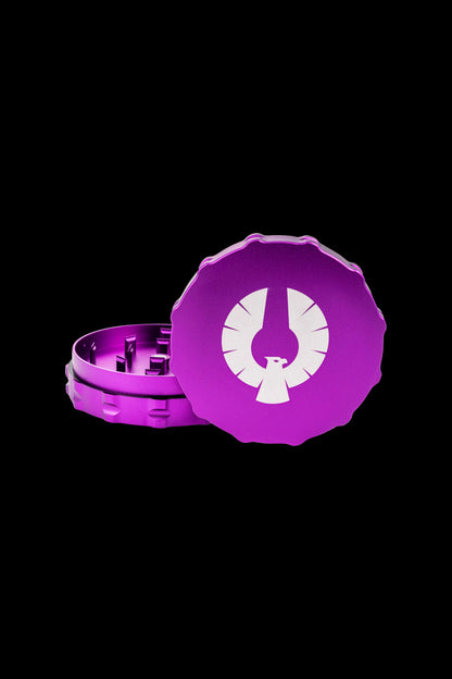 Purple cannabis grinder with a white phoenix logo, partially disassembled.