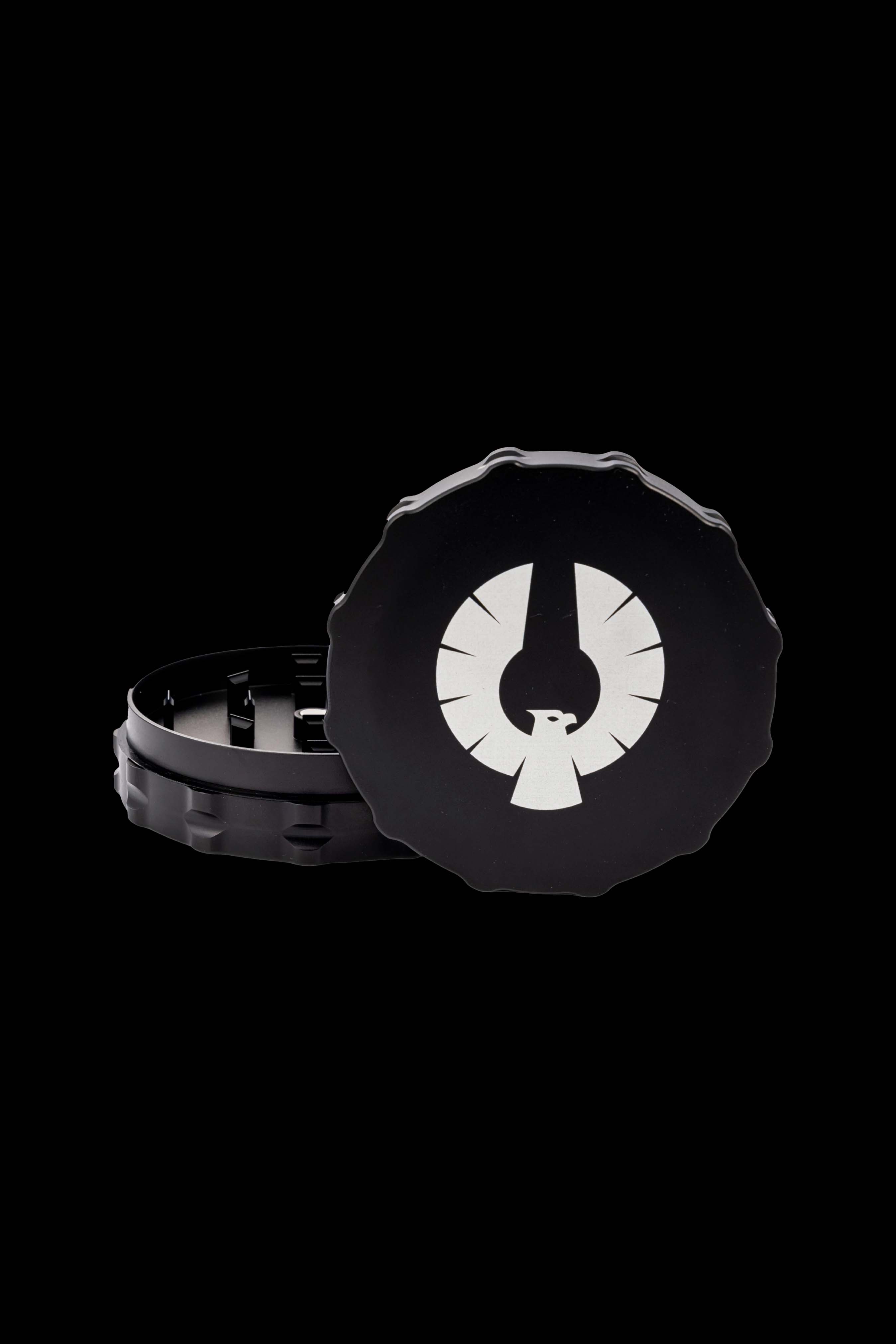Black metal cannabis grinder with a white stylized bird logo on the lid, partially open to reveal the internal grinding mechanism.