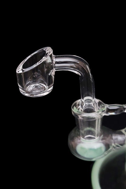Clear glass dab rig with a quartz banger, isolated on a black background.
