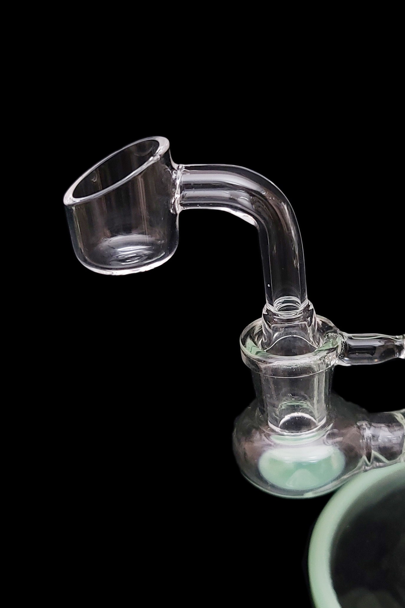 Clear glass dab rig with a visible bucket and water chamber, isolated on black.