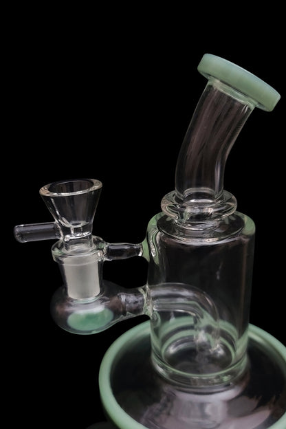 A clear glass bubbler with a green accent, featuring a bowl and water chamber, isolated on a black background.