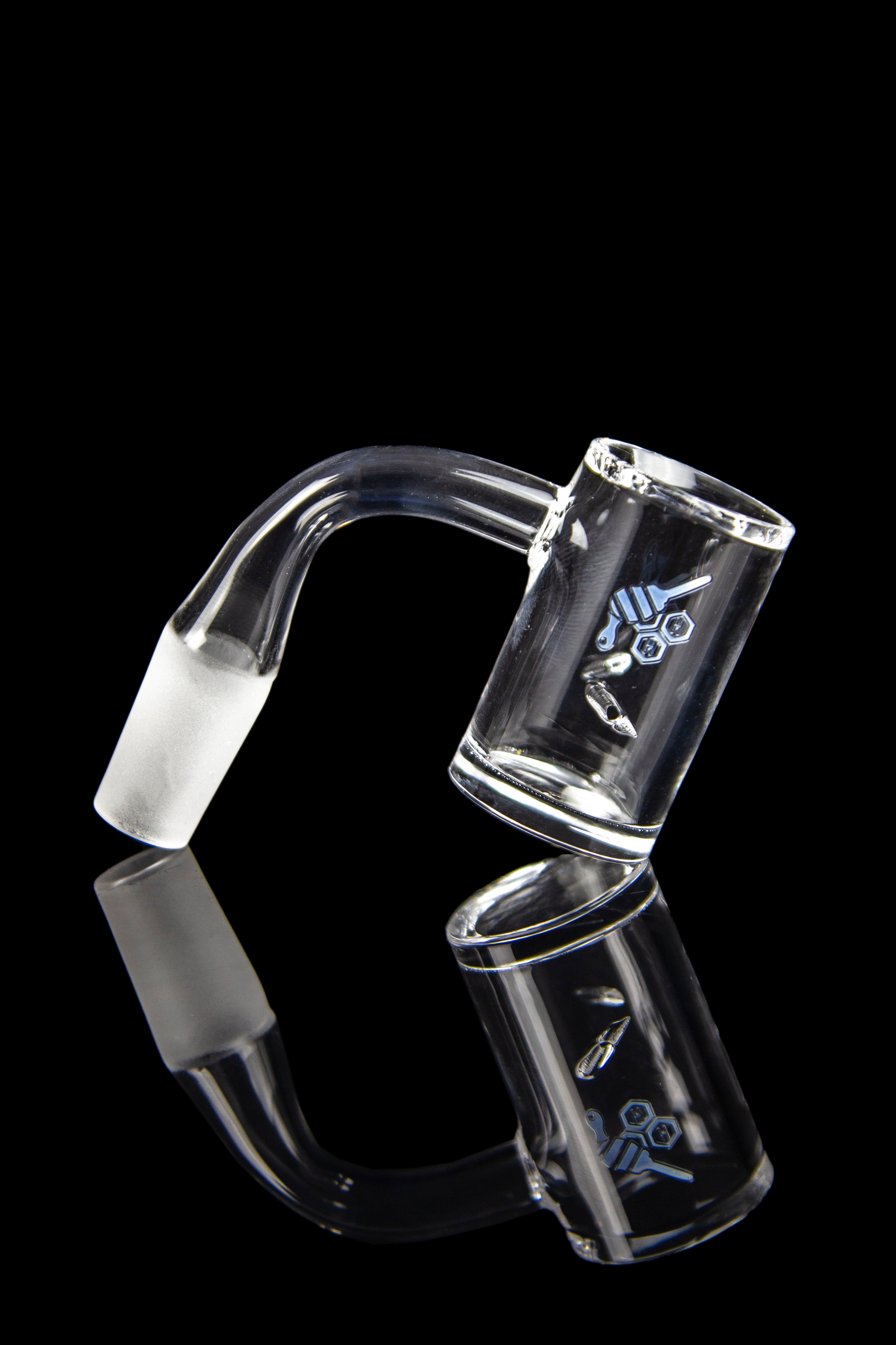 Clear glass dab rig with intricate etched design, reflected on a black surface.