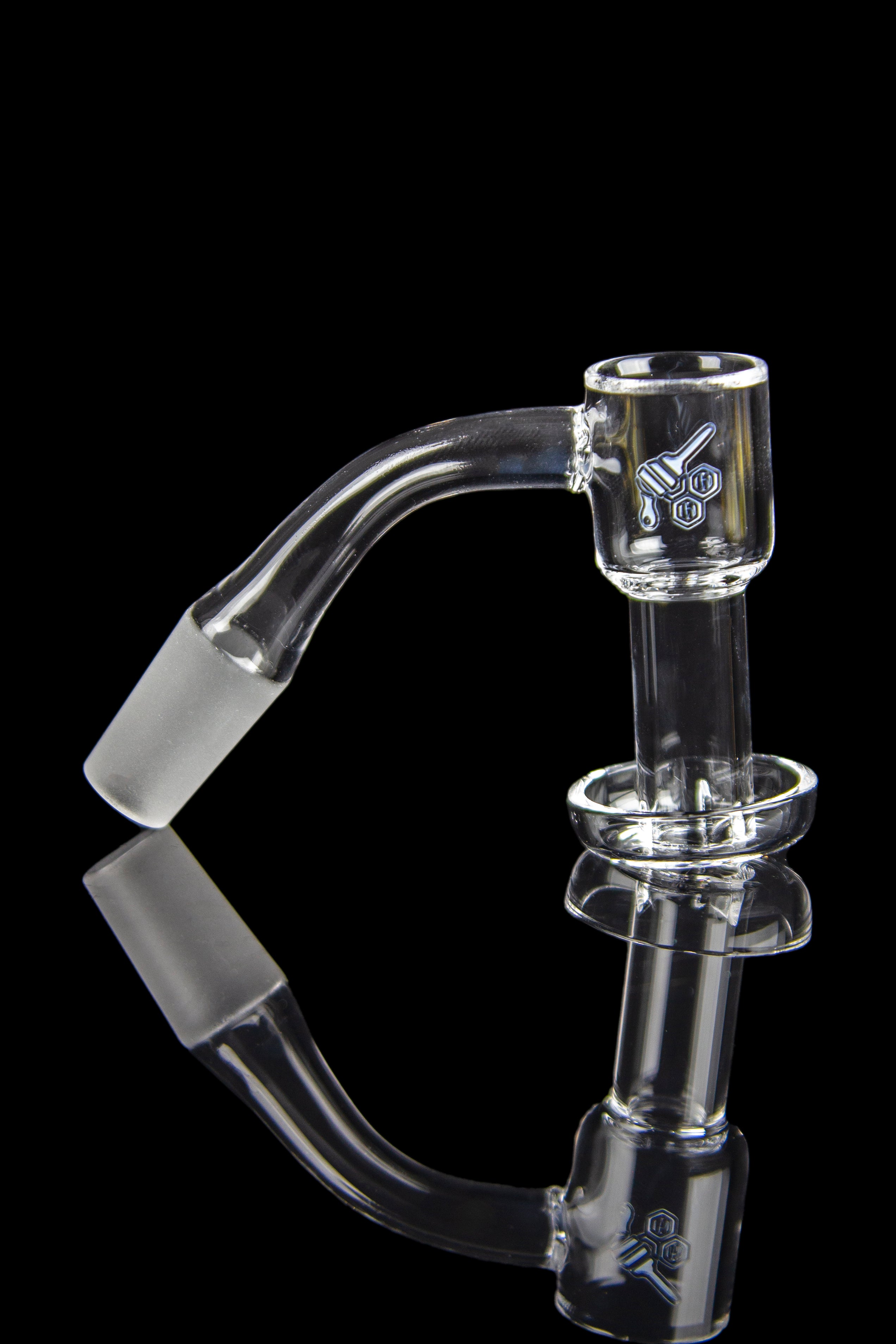 Clear glass dab rig with a bent neck and detailed etching, reflected on a black surface.