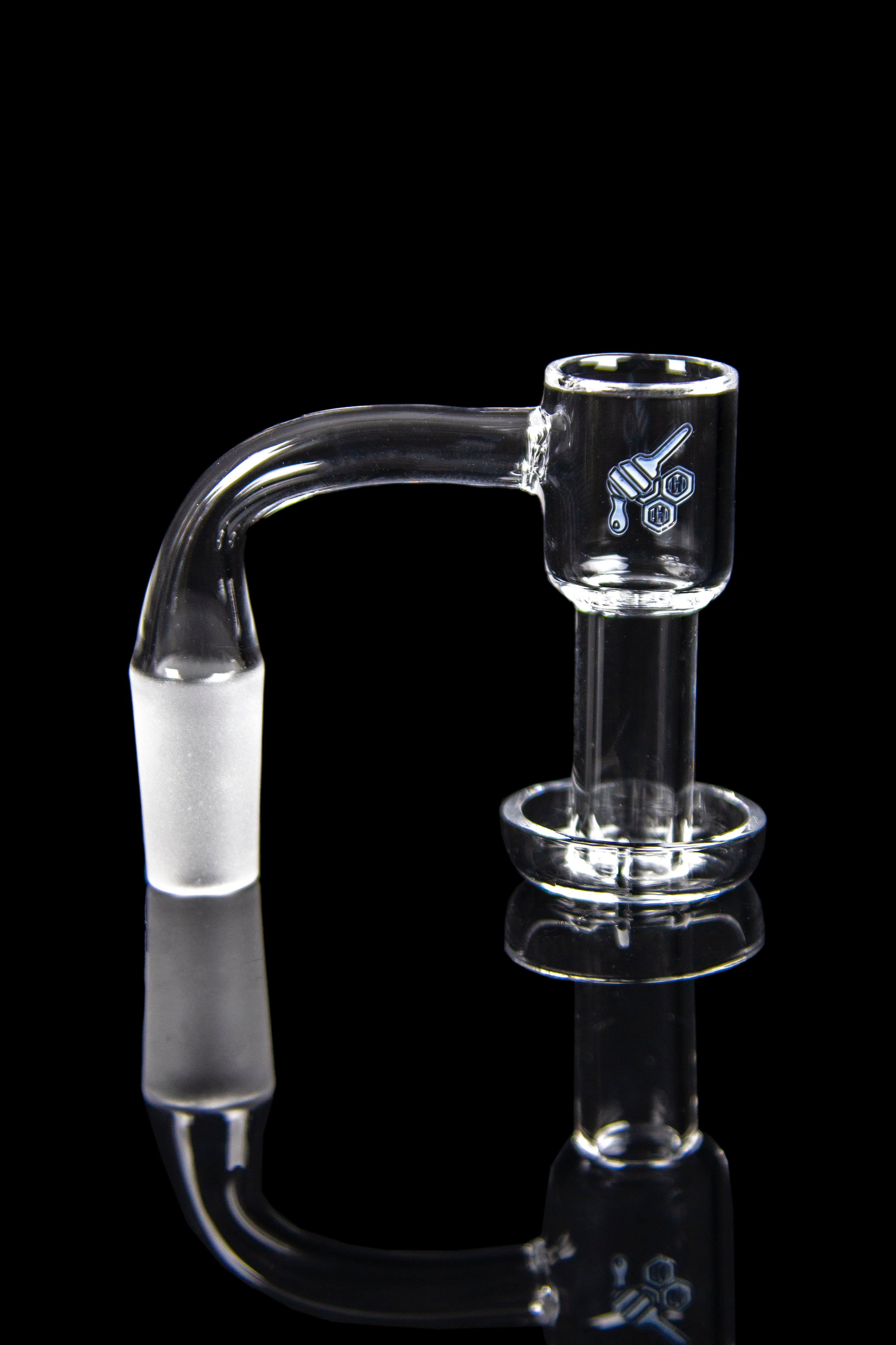 Clear glass dab rig with a bent neck and quartz banger, reflected on a black surface.