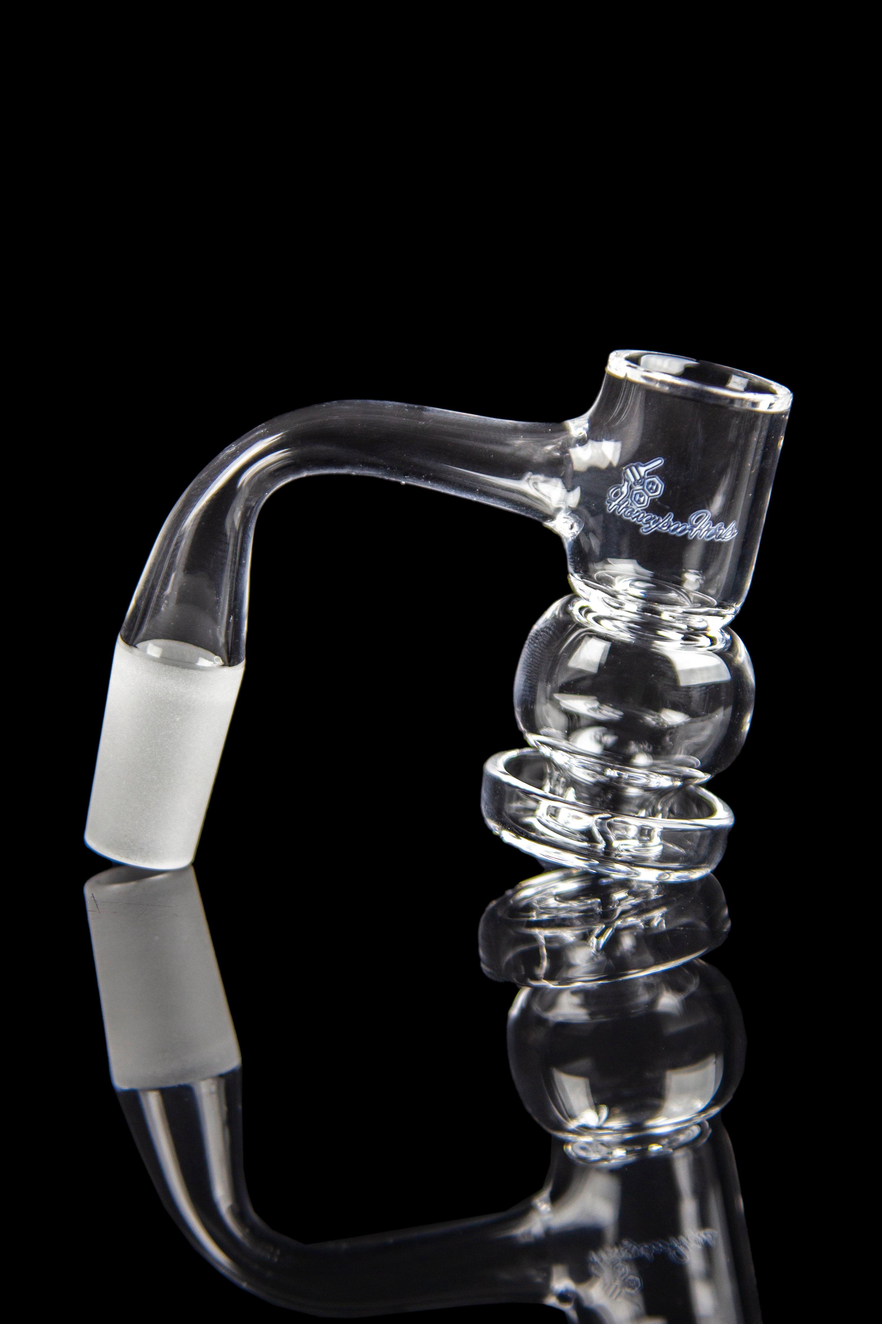 Clear glass bubbler with bulbous chambers and a bent mouthpiece, reflected on a black surface.