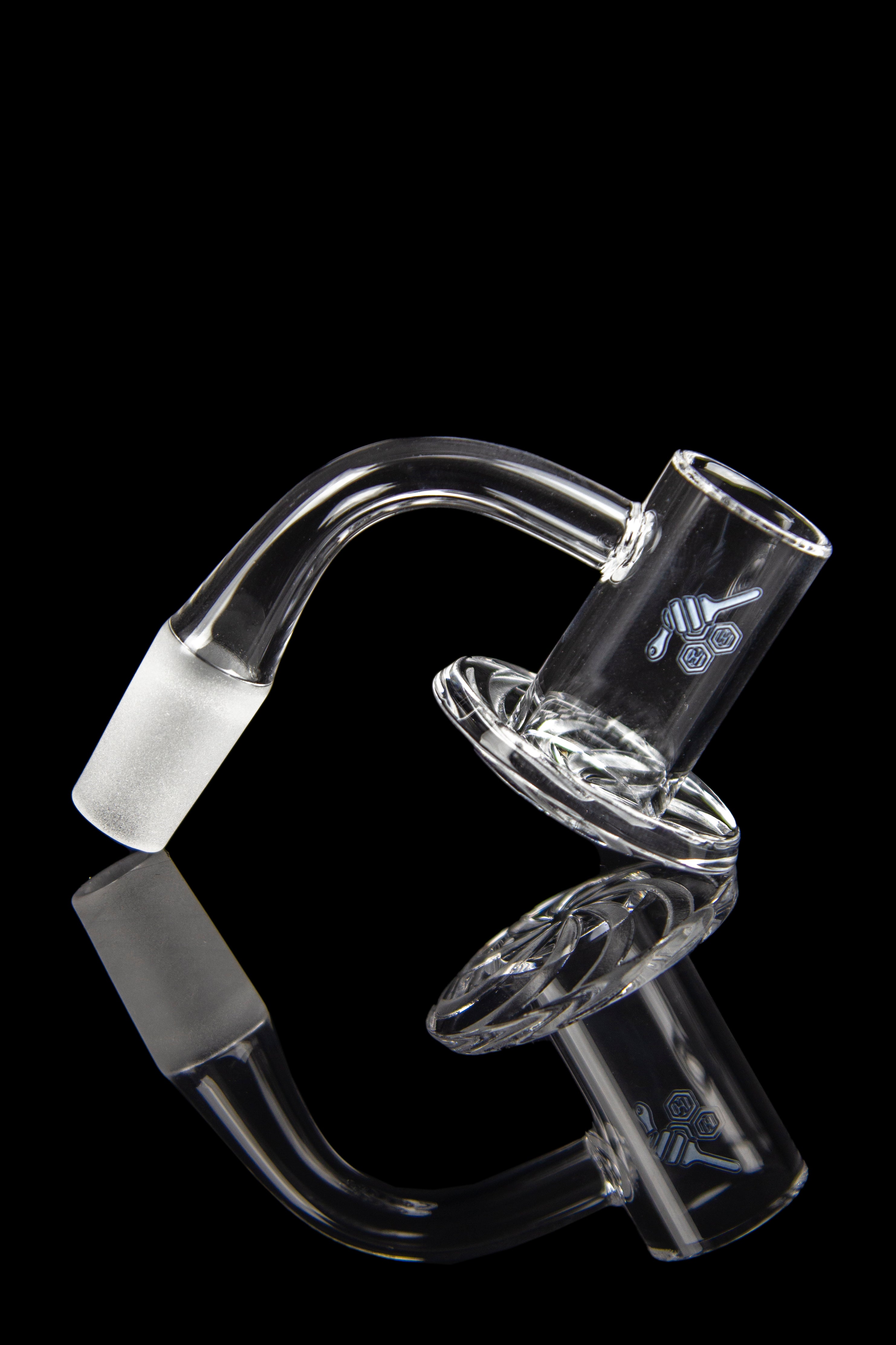 Clear glass dab rig attachment with intricate swirling design and frosted joint, reflected on a black surface.