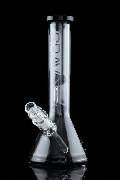Clear glass bong with a flared base and downstem, reflecting on a black surface.