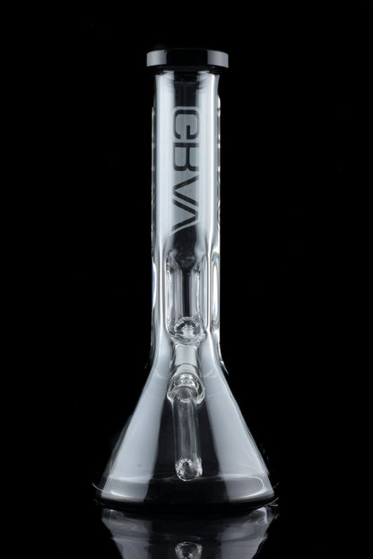 Clear glass water pipe (bong) with ice catch and brand logo, reflecting on a dark surface.