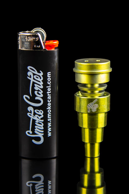 Gold-toned oil burner pipe and black lighter with "Smoke Cartel" branding on a reflective black surface.