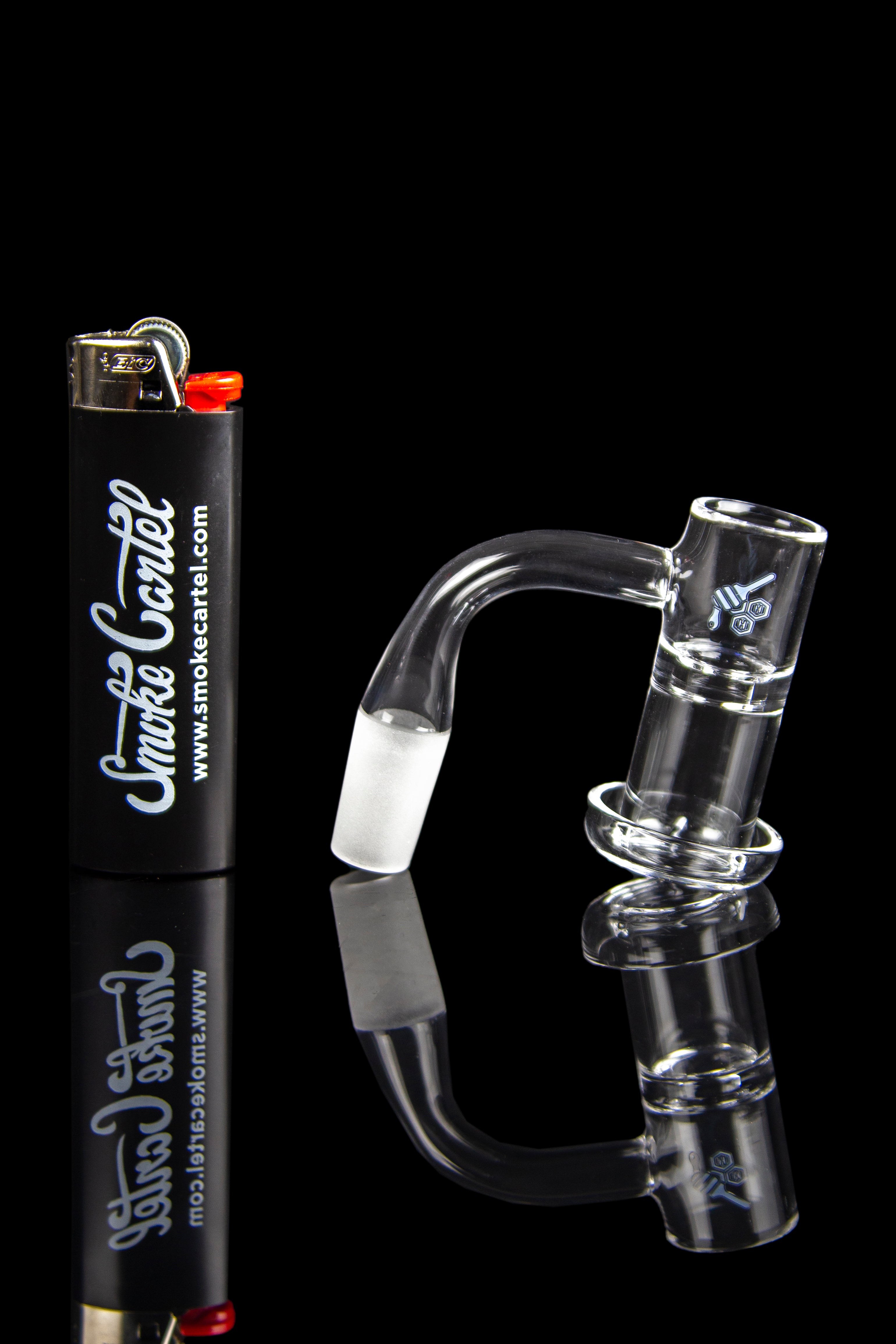 Glass dab rig and lighter with branding for Smoke Cartel, reflected on a dark surface.