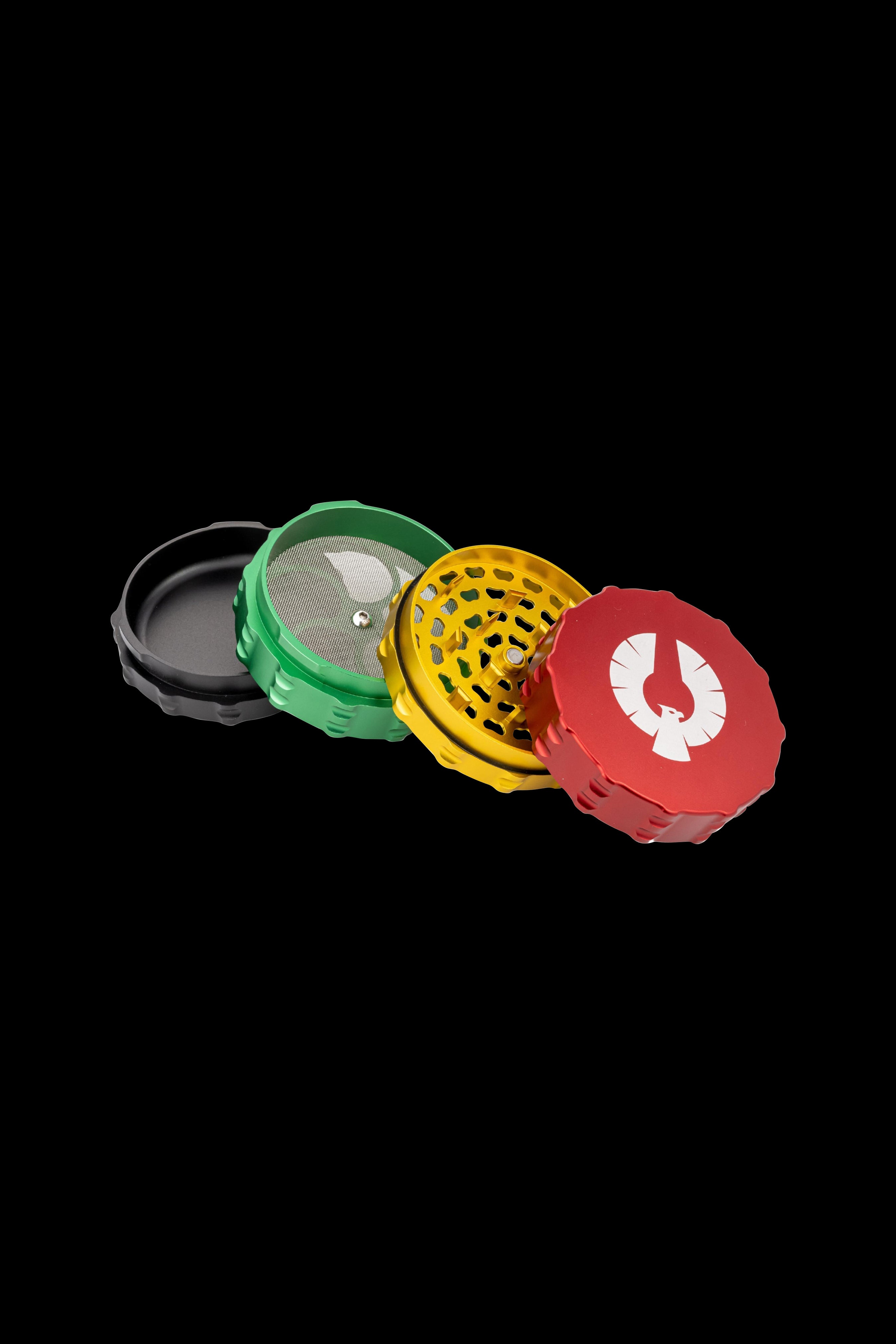 Four-piece metal grinder in red, gold, green, and black, disassembled and laid flat on a white surface.