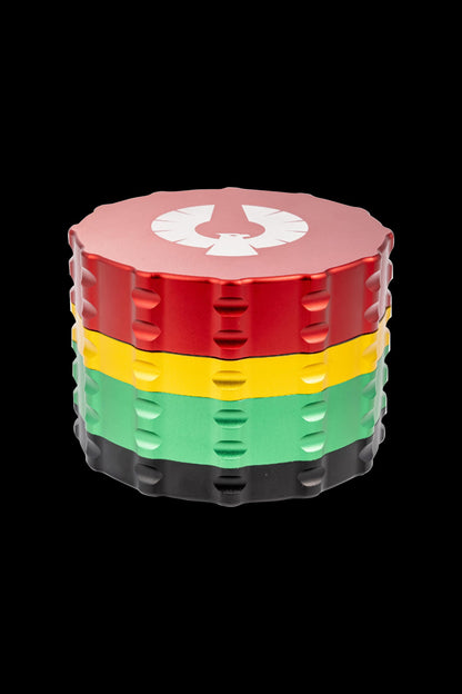 Four-layer metal grinder with red, yellow, green, and black tiers, featuring a white emblem on the lid.