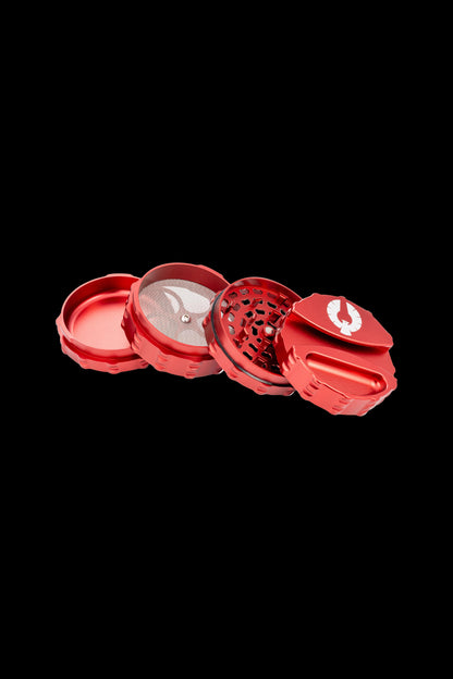 Red four-piece cannabis grinder with visible ground herb.