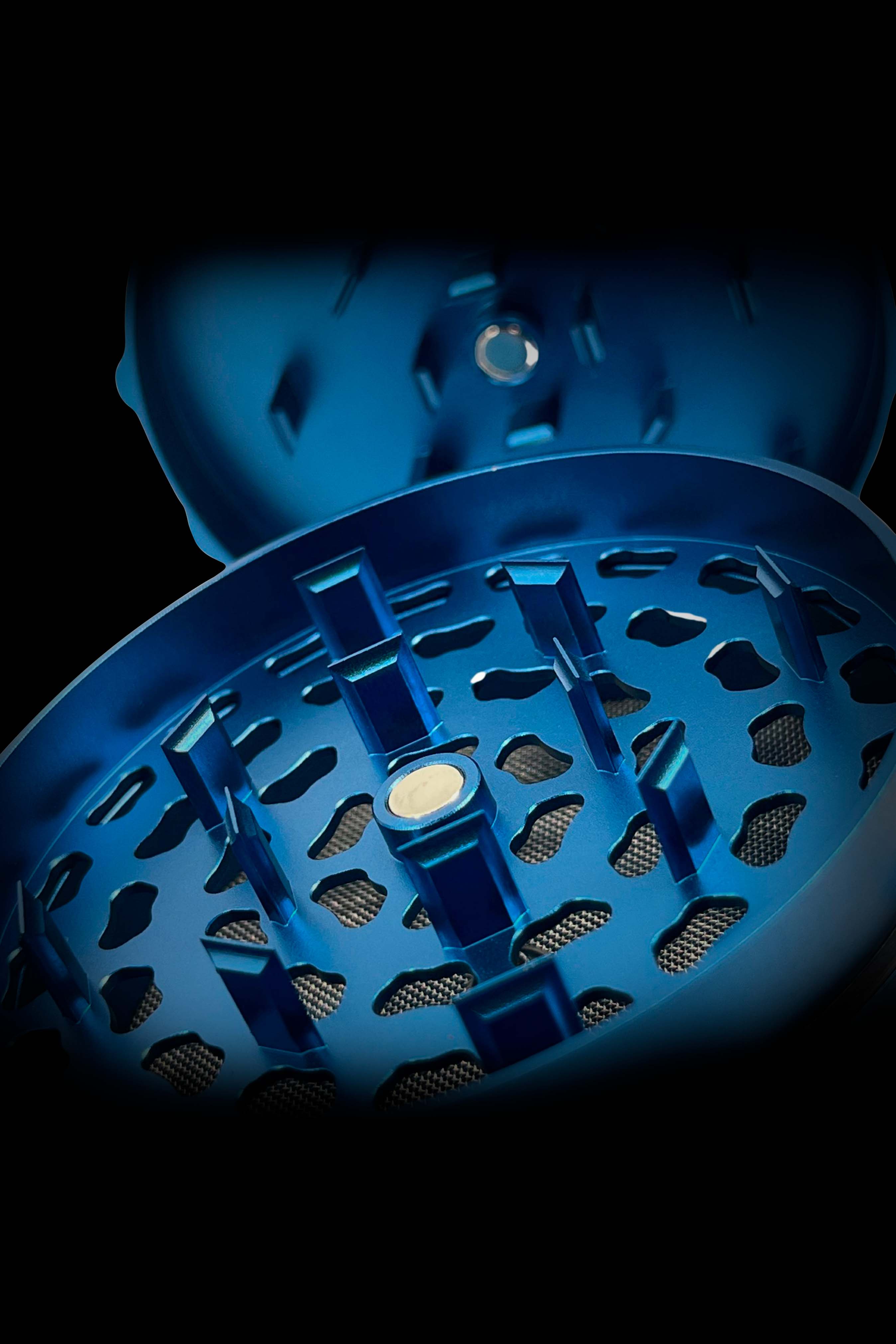 Close-up of a blue cannabis grinder with a mesh screen and magnetic closure.