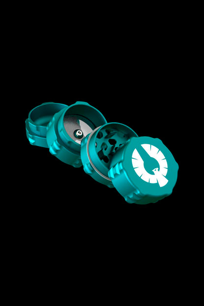 Teal four-piece cannabis grinder disassembled on a black background.