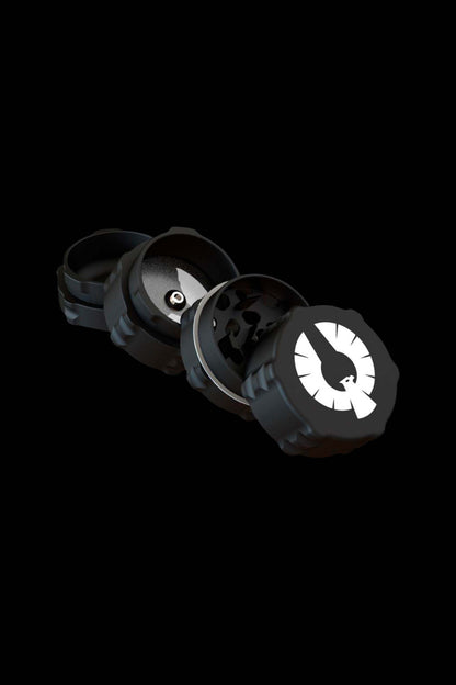 Black cannabis grinder disassembled, showing individual parts against a dark background.