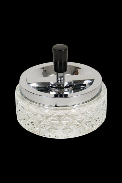 A close-up, angled view of the Glass Spinning Ashtray, showcasing its clear glass construction and circular design.