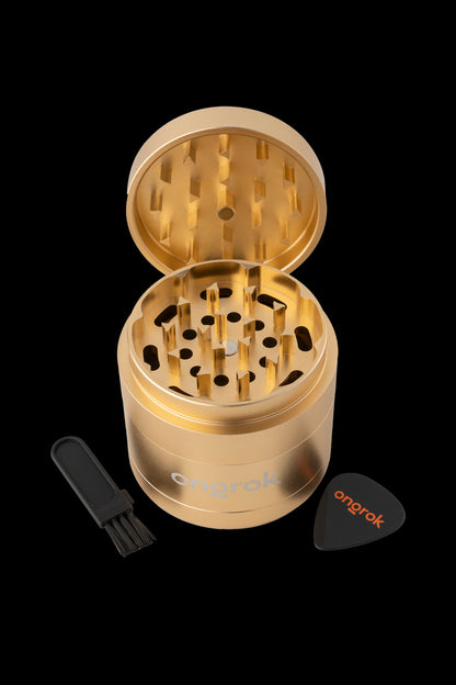 Gold cannabis grinder with cleaning brush and pick.