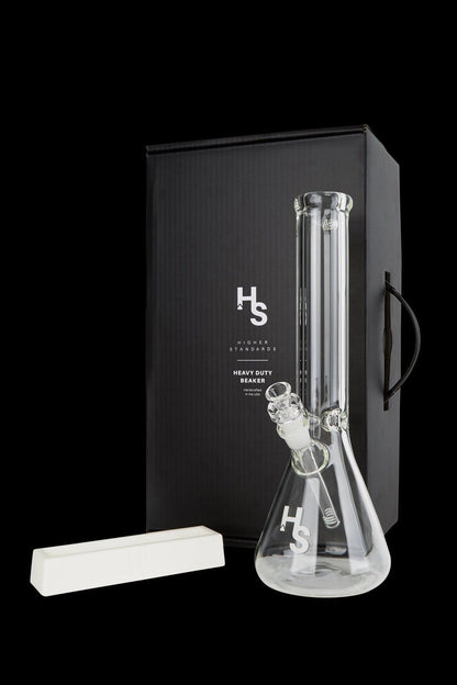 A glass water pipe (bong) from Higher Standards, displayed in its box with a cleaning brush.