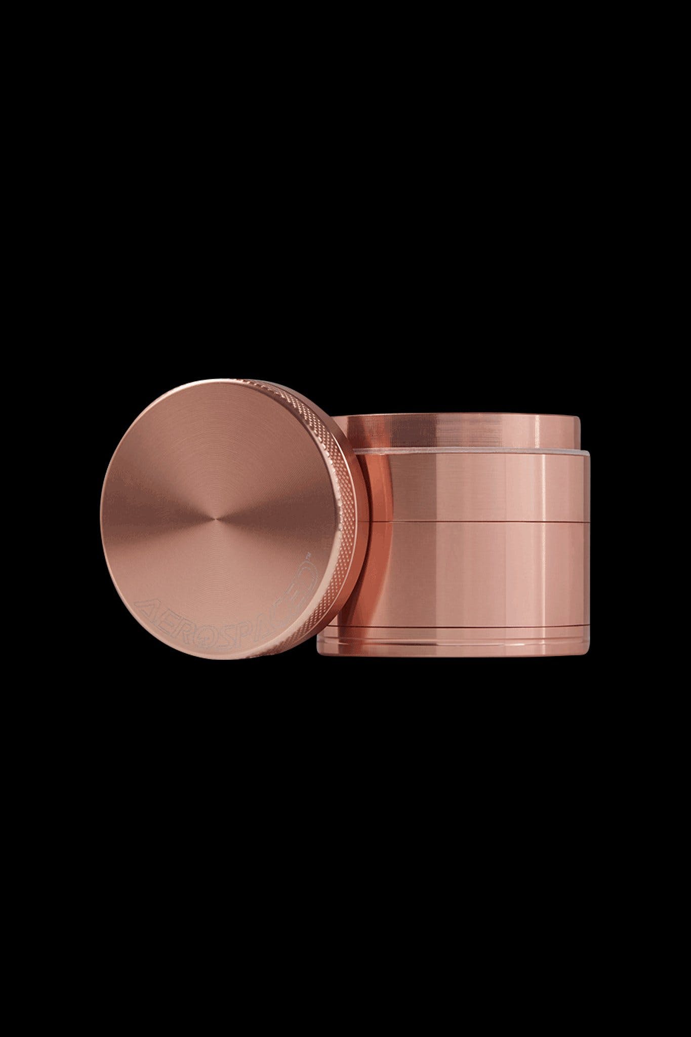 Copper cannabis grinder with lid removed, isolated on black.