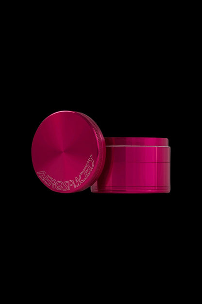Hot pink cannabis grinder with “AEROSPACED” etched on the lid.