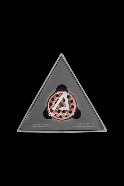 Triangle-shaped, clear acrylic container displaying a copper-toned four-piece cannabis grinder with the “AEROSPACED” logo.