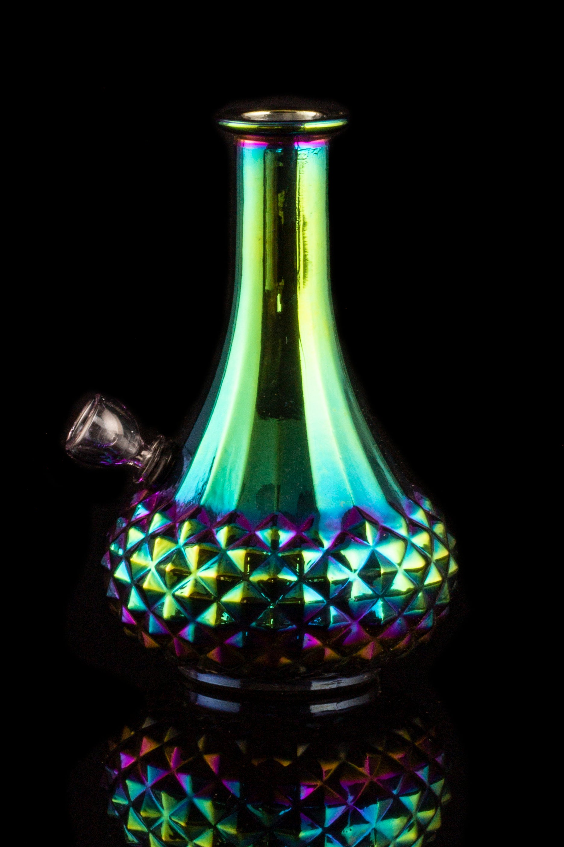 Iridescent glass water pipe with a geometric patterned base, isolated on black.