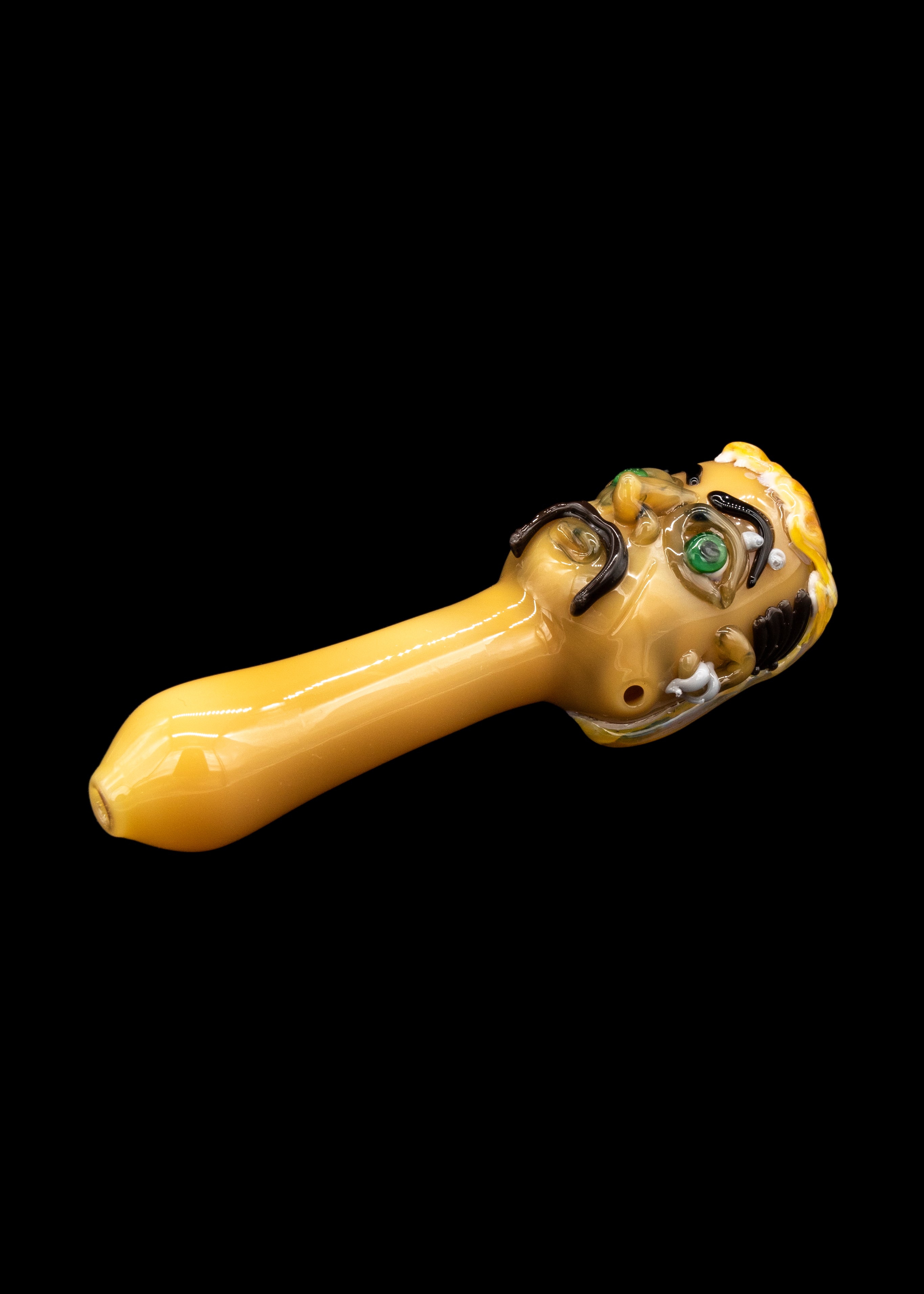 Glass pipe with a monster-themed design, isolated on a black background.