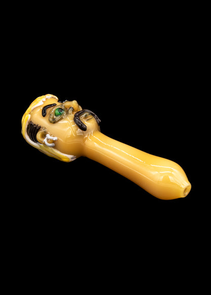 Hand-blown glass pipe with a skull design, isolated on a black background.