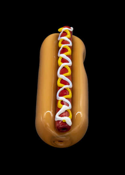 Glass pipe shaped like a hot dog with mustard and relish, against a black background.