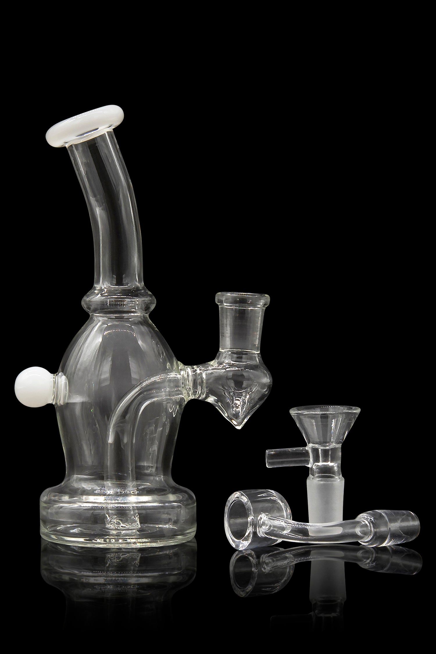 Clear glass bubbler water pipe with accompanying bowl and accessories, reflecting on a dark surface.
