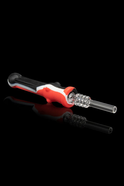 Red and black silicone dab tool with a glass tip, reflecting on a black surface.