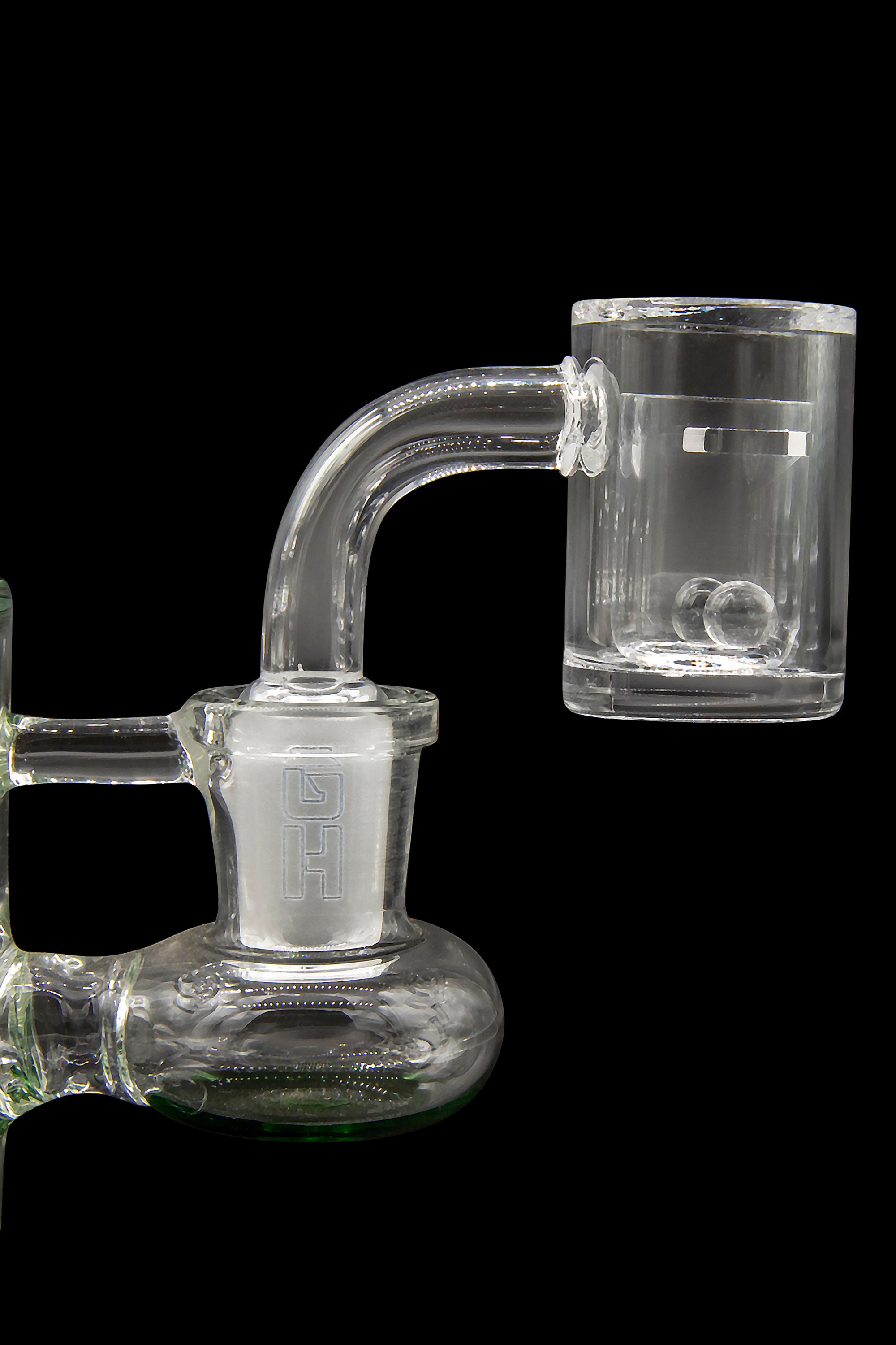 Clear glass dab rig with quartz banger, isolated on a black background.