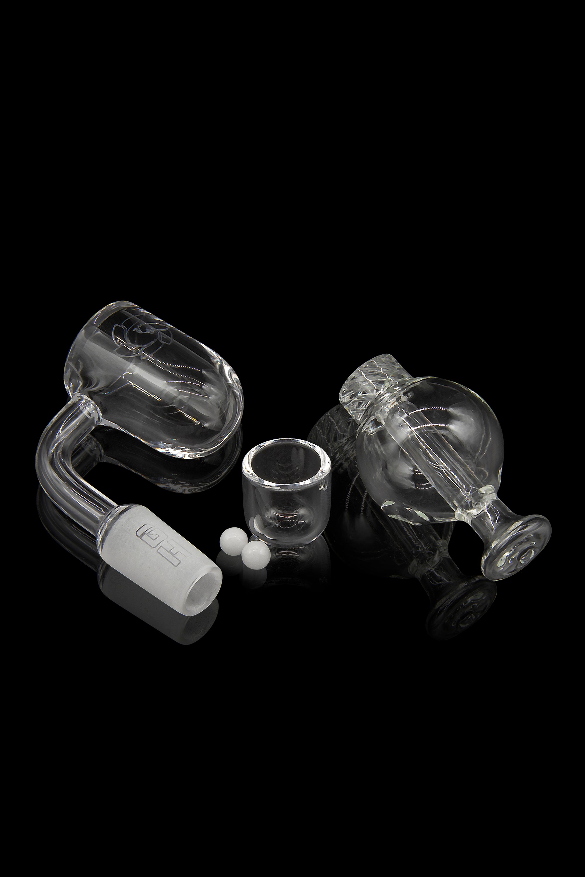 Glass dab rig kit with carb cap, banger, and insert, isolated on a black background.