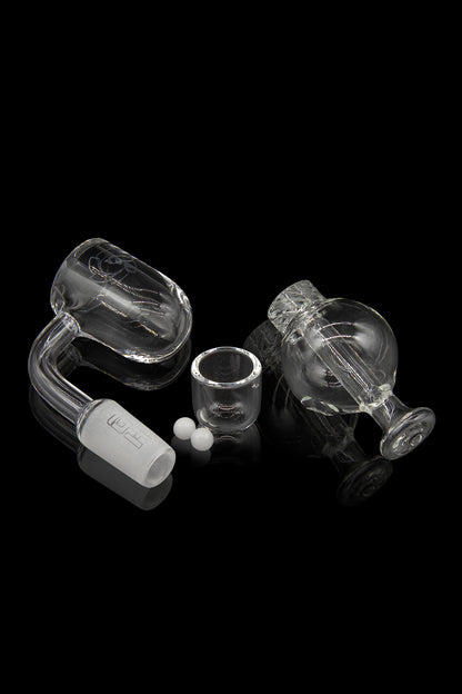 Glass dab rig kit with carb cap, banger, and insert, isolated on a black background.