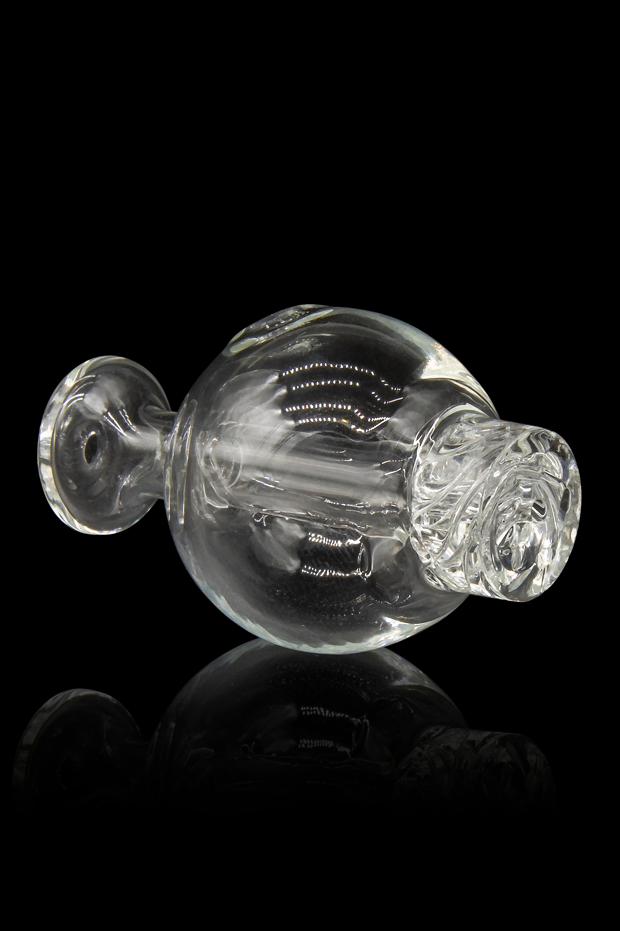 Clear glass water pipe with spherical body and dual mouthpieces, reflected on a black surface.