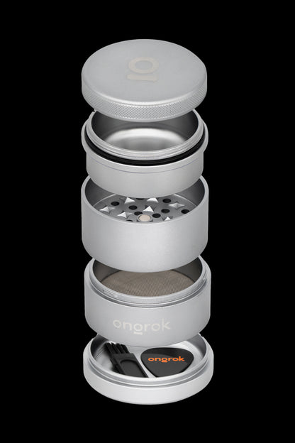 Silver cannabis grinder disassembled, showing multiple chambers and a cleaning brush in a bright orange base.