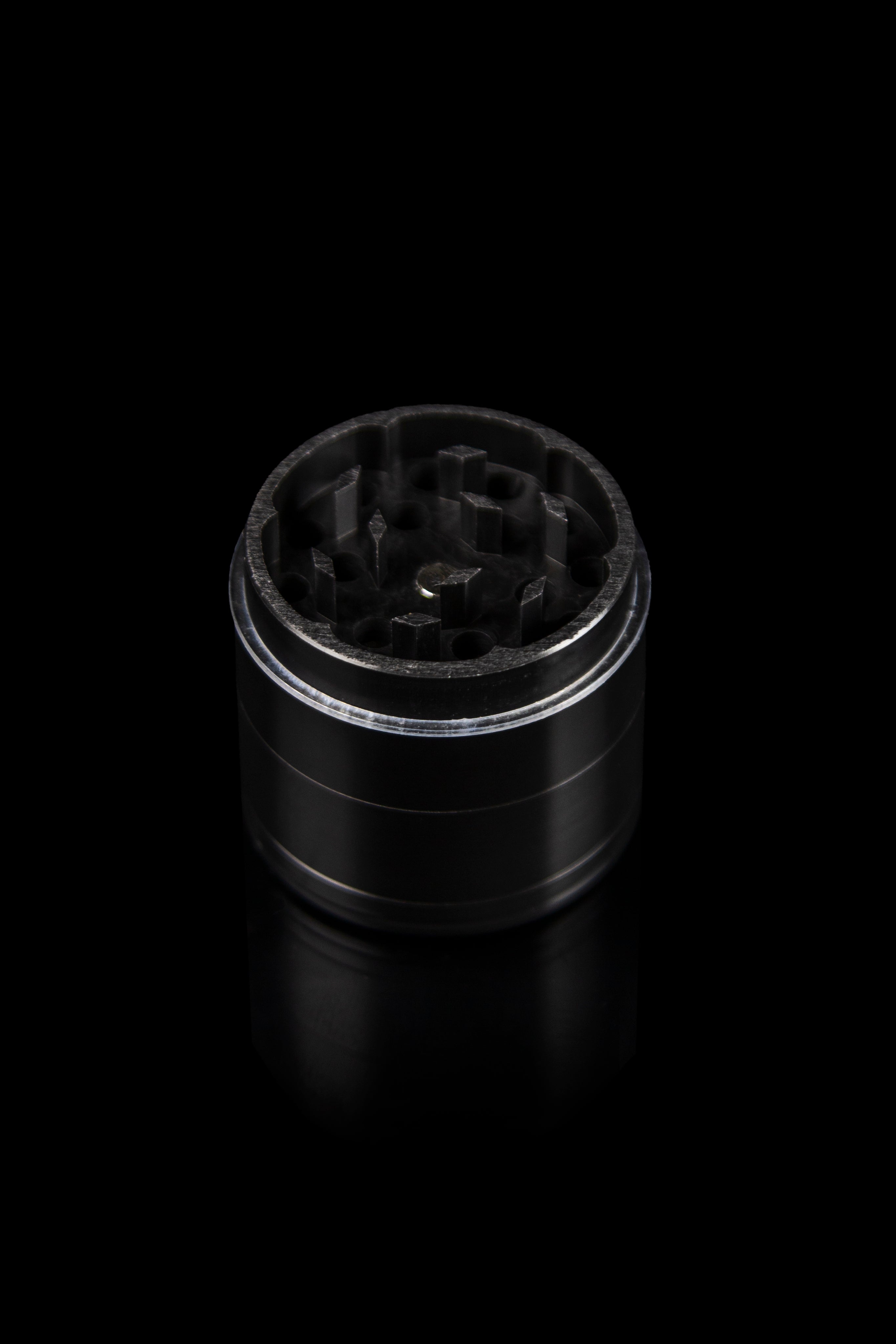 Black metal cannabis grinder isolated on a dark background.