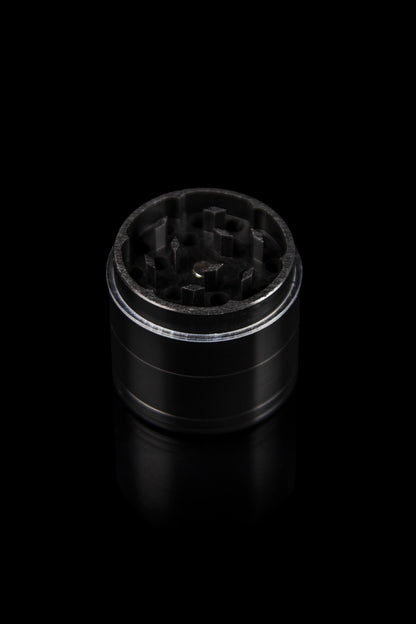 Black metal cannabis grinder isolated on a dark background.