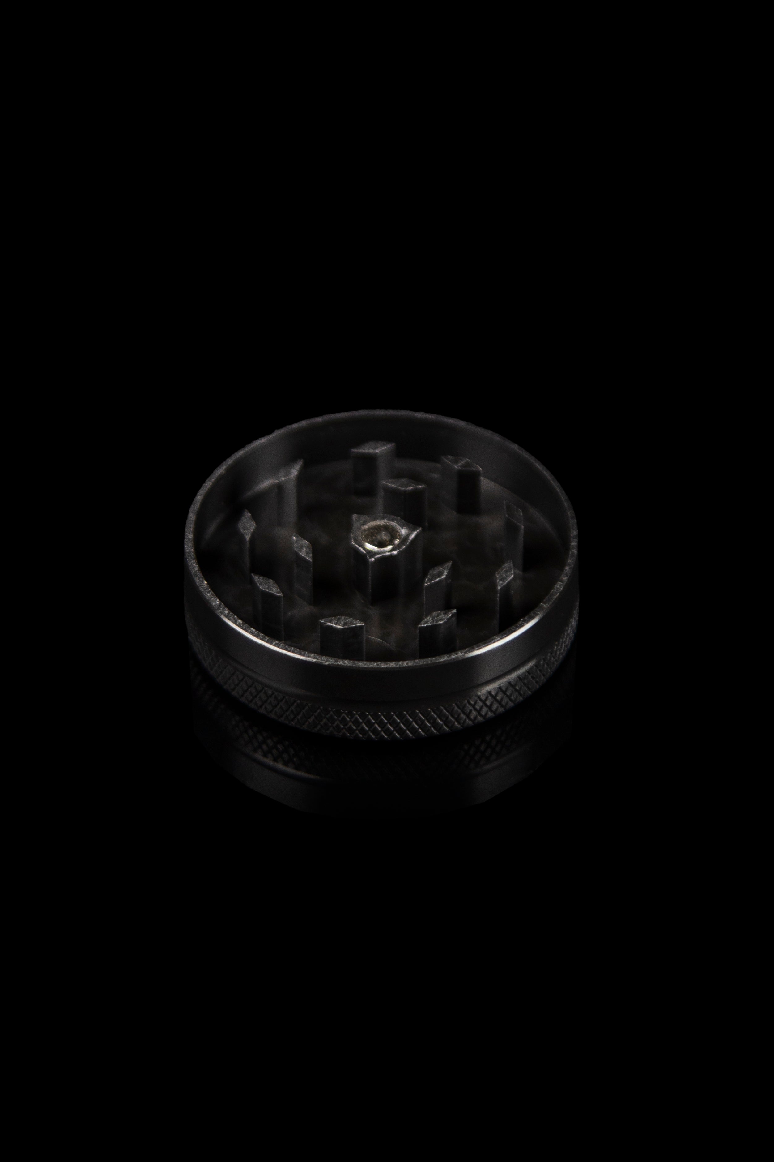 Black metal cannabis grinder against a dark background.