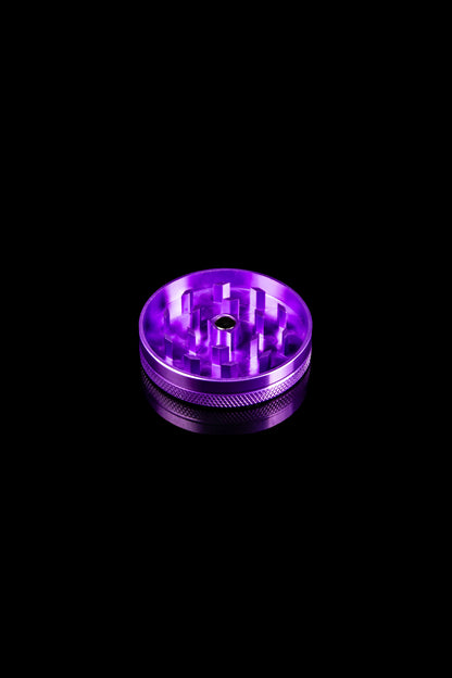 Purple metal cannabis grinder on a black background.